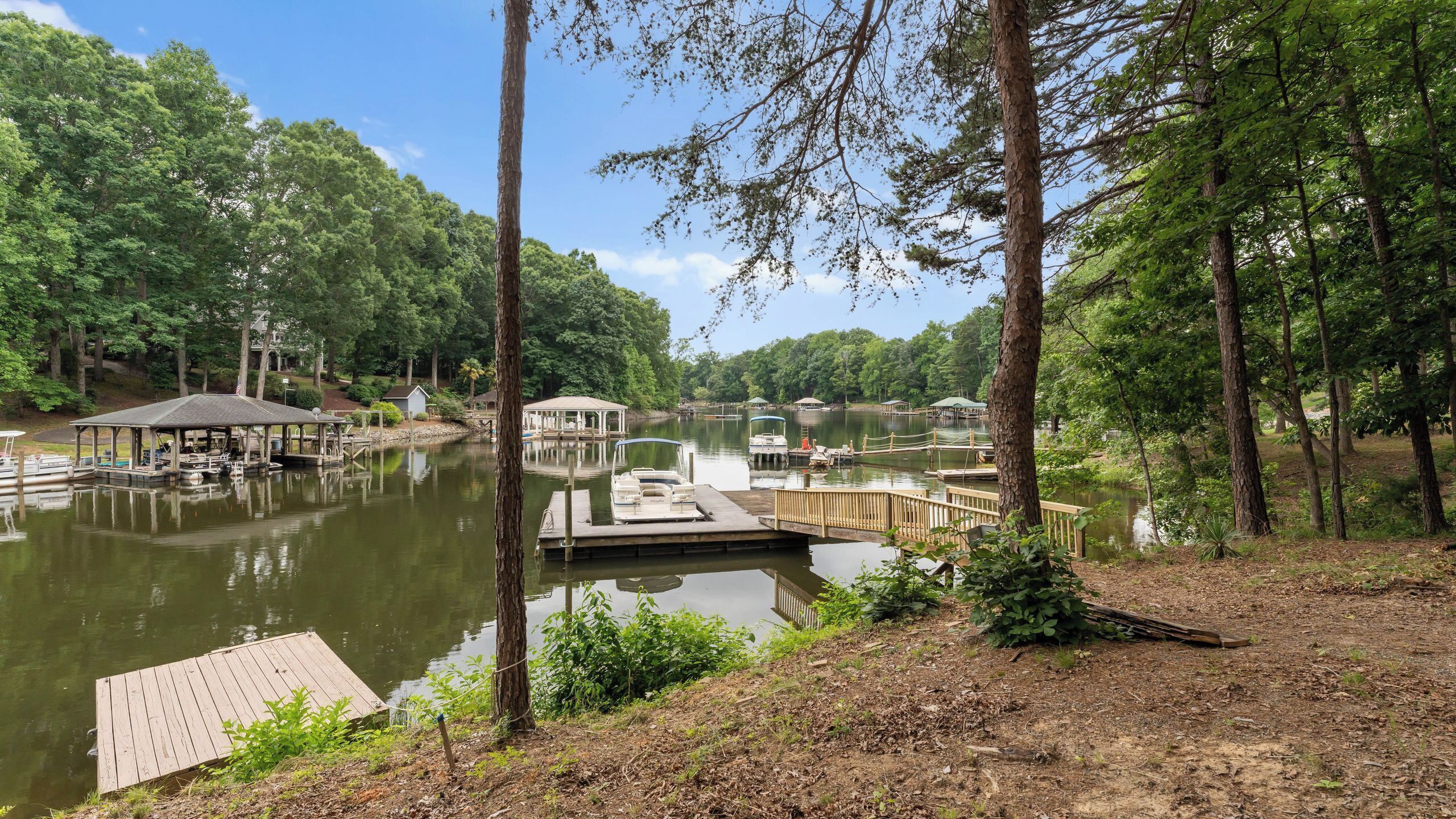 A lakeside dock with boats, a gazebo, and a wooden pier.