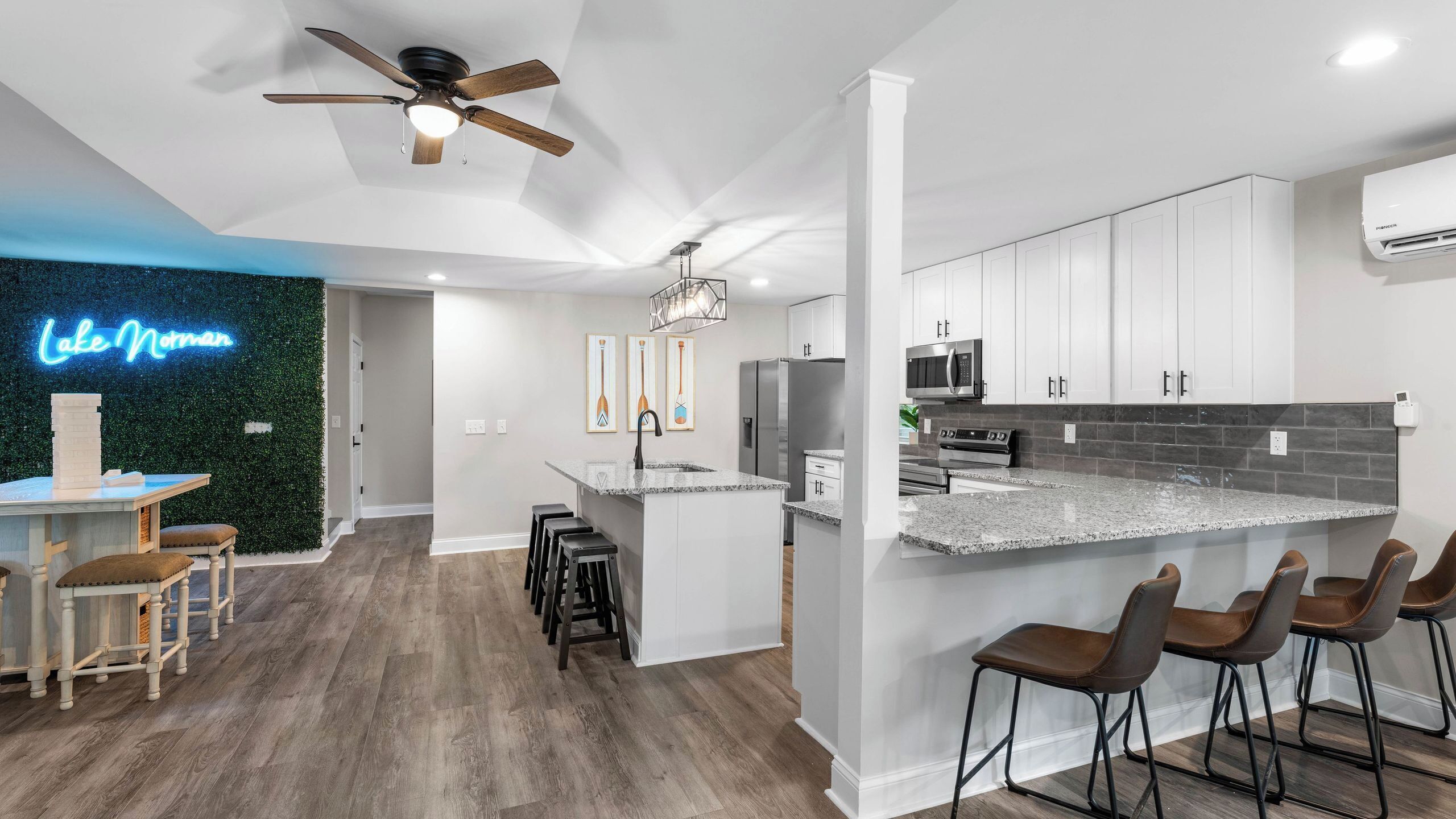 A modern kitchen with white cabinets, a granite countertop, and a ceiling fan.