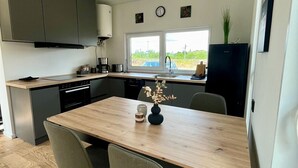 A modern kitchen with a wooden table, two chairs, and a refrigerator. - Where time is lost in the green and relaxation is at home? (Altefähr)