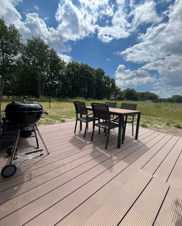 An outdoor deck with a grill and four chairs. - Where time slips away amid the greenery, and relaxation is right at home? (Altefähr)