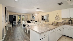 A spacious kitchen with white cabinets, a marble countertop, and a dining area with a table and chairs. - Beachside with peekaboo beach view/ heated pool (Madeira Beach)