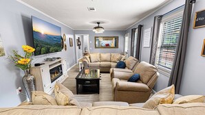 A living room with a fireplace, sofa set, and a television mounted on the wall.