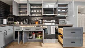 Eine moderne Küche mit grauen Schränken, einem eingebauten Backofen, einer Mikrowelle und einem Toaster.