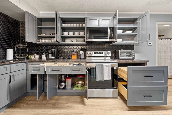 Una cocina moderna con armarios grises, horno empotrado, microondas y tostadora.