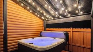 Ein Whirlpool in einer Holzhütte mit einer Holzterrasse und einem Holzzaun.