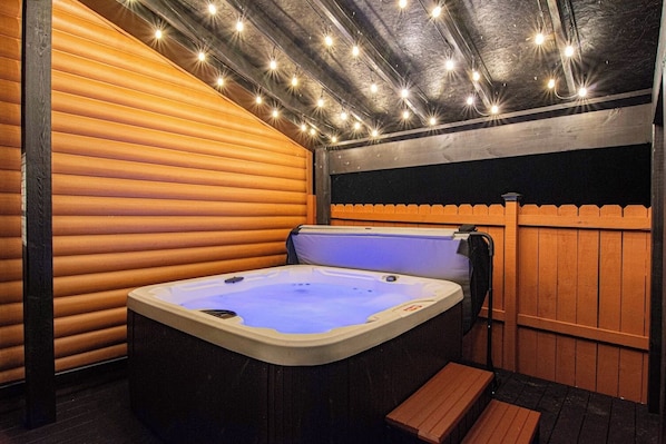 Un jacuzzi en una cabaña de madera con terraza y valla de madera.