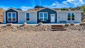 A modern two-story building with a flat roof, large windows, and a gravel driveway.