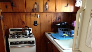 A compact kitchen with wooden cabinets, a white stove, and a refrigerator. - Central air, dog friendly walk to beach in this 2 bedroom family cottage  (Dennis)