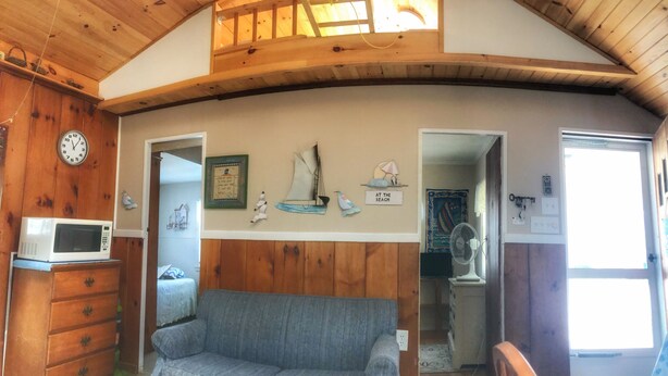 A cozy cabin interior with a wooden ceiling, a sofa, a microwave, and nautical-themed decorations. - Central air, dog friendly walk to beach in this 2 bedroom family cottage  (Dennis)