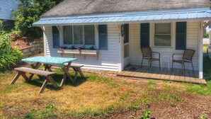 A small house with a porch, a table, and two chairs. - Central air, dog friendly walk to beach in this 2 bedroom family cottage  (Dennis)