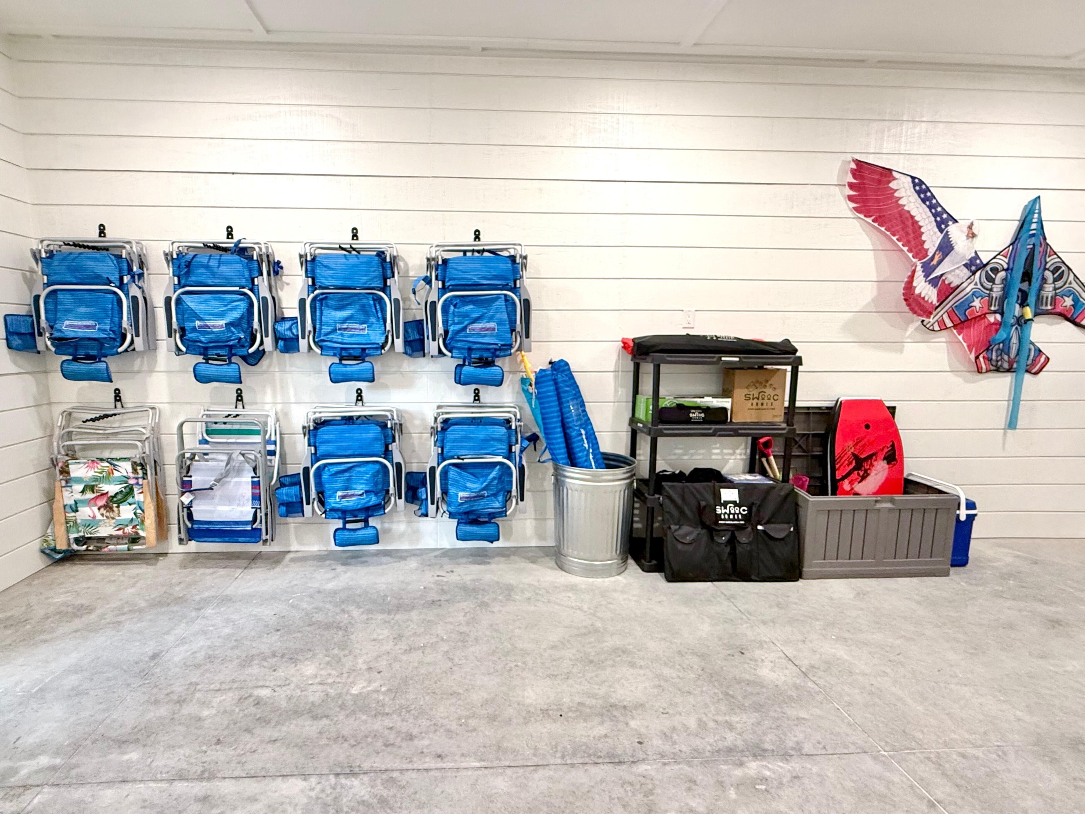 A room with multiple blue chairs, a trash can, a shelf with bags, and a decorative item on the wall.