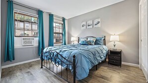 A bedroom with a bed, a nightstand, a window with curtains, and artwork on the wall. - Relaxing 2BR Riverfront Townhome (Yorkville)