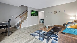 A modern living room with a staircase, a dining area, and a seating area with a sofa and coffee table. - Relaxing 2BR Riverfront Townhome (Yorkville)