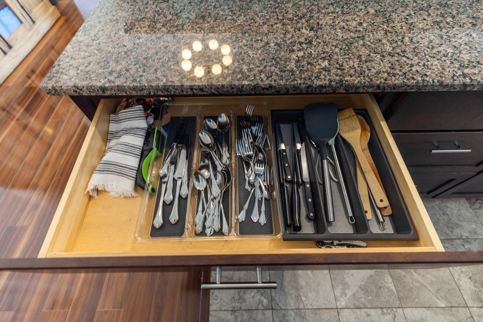 A drawer with neatly organized kitchen utensils and a striped towel.