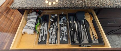 A drawer with neatly organized kitchen utensils and a striped towel.