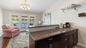 A modern kitchen with dark cabinetry, a granite countertop, and a hanging light fixture. - Riverwalk Retreat - Downtown water views, parking (Wilmington)