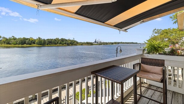 A balcony with a view of a river, a table, and a chair. - Riverwalk Retreat - Downtown water views, parking (Wilmington)