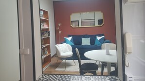 A living room with a sofa, a dining table, a bookshelf, and a mirror. - Cosy town house with bicycles available (Tours)