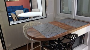 A compact kitchen with a wooden table and chairs, a microwave, and a window with blinds. - Cosy town house with bicycles available (Tours)