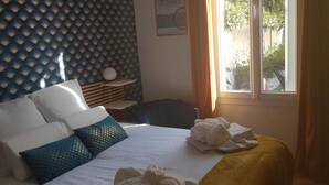 A hotel room with a bed, a bedside table, a window with curtains, and a wall with a patterned design. - Cosy town house with bicycles available (Tours)