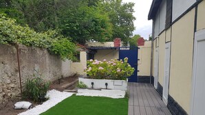 A small, well-maintained garden with a wooden deck, a white flower bed, and a blue door. - Cosy town house with bicycles available (Tours)