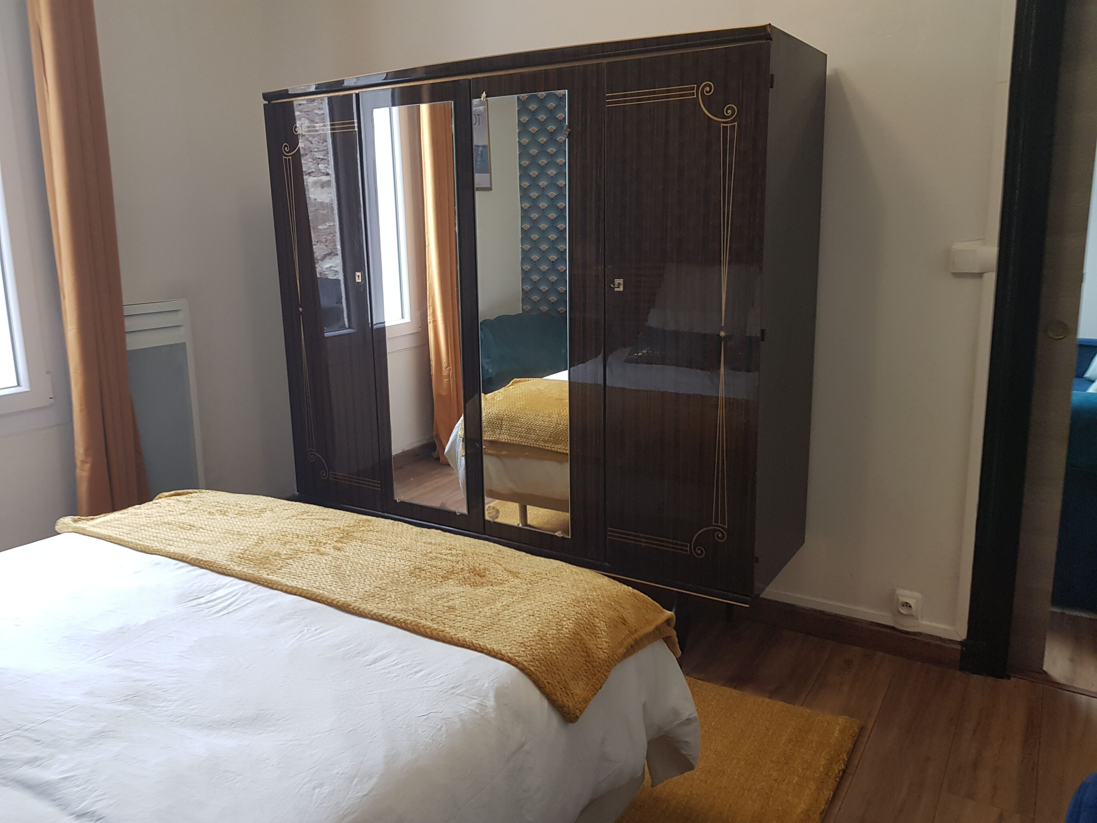 Une chambre à coucher avec un lit, une armoire et une fenêtre avec des rideaux.