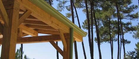 A wooden pergola structure with a clear view of tall pine trees in the background.