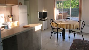 Une cuisine compacte avec un coin repas, un téléviseur et une fenêtre donnant sur un espace verdoyant.