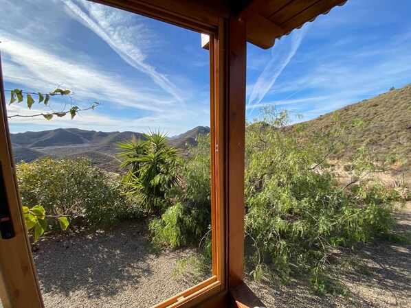 A window view of a desert landscape with mountains in the background.