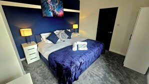 Camera da letto con un letto, due comodini, una mensola portaoggetti e un quadro appeso al muro.