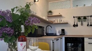 Une cuisine moderne avec une table à manger dressée pour deux personnes, une bouteille de vin rosé et un verre.