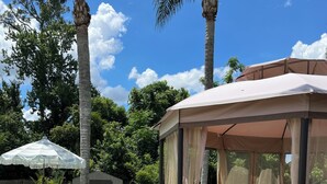 A poolside area with a covered seating area, lounge chairs, and a pool. - Resort Style Home Near Universal/Disney (Orlando)