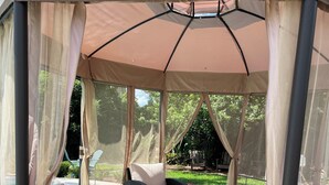 A covered outdoor seating area with wicker furniture and a cushioned bench. - Resort Style Home Near Universal/Disney (Orlando)