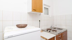 Een kleine keuken met witte tegels, een houten kast, een fornuis en een spoelbak.