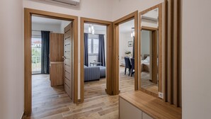 A modern hotel room with a wooden wardrobe, a bed, a desk, and a dining area. - Holiday Home Milutin 1 - Four Bedroom Holiday Home with Private Pool (Vrsi)