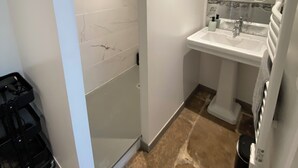 Un baño moderno con cabina de ducha de vidrio, un lavabo blanco y un espejo.