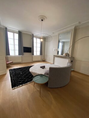 Une chambre à coucher moderne avec un lit rond, une petite table de chevet, un grand miroir et un luminaire au plafond original.