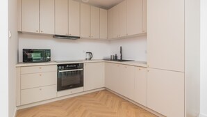 Una cuina moderna amb armaris blancs, microones, cafetera i rentaplats.
