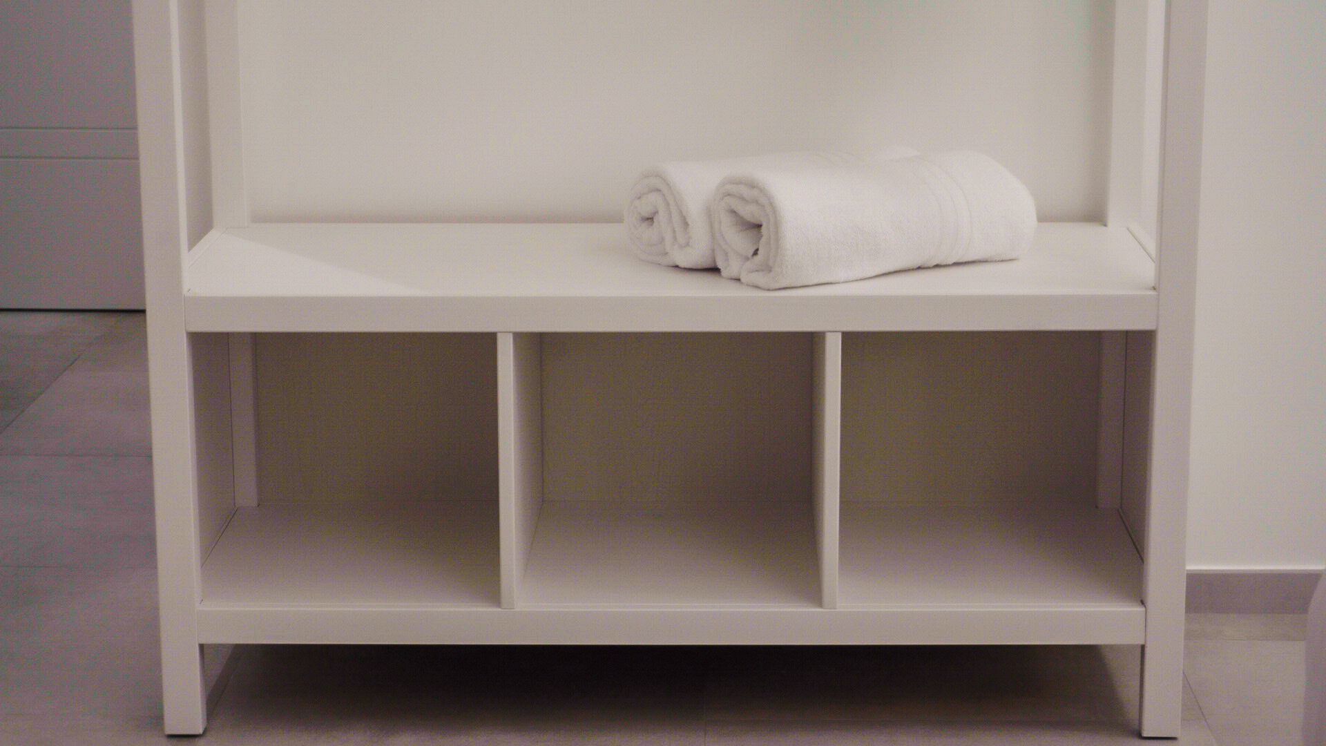 Een witte plank met twee opgerolde handdoeken.