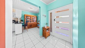 Una cocina con armarios blancos, un mueble de madera con puertas de vidrio y una zona de comedor con una silla y una mesa.