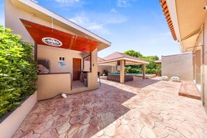 Un espace extérieur abrité comprenant un coin barbecue, une piscine et un espace détente avec des sièges.