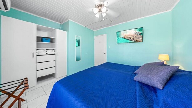 Un dormitorio con cama, armario, ventilador de techo y un cuadro en la pared.