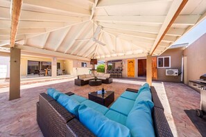 Une terrasse extérieure couverte, aménagée avec un canapé, une table basse et un coin repas.