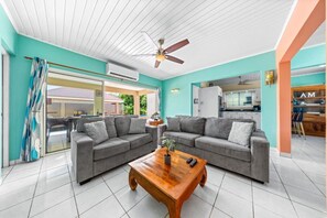 A living room with two grey sofas, a wooden coffee table, and a ceiling fan. - Stunning Villa Near Beaches W/Pool 4Br&3Ba (Noord)