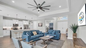 Un vaste espace de vie comprenant un canapé bleu, une table basse en bois et un ventilateur de plafond.