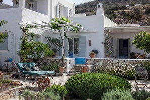 A white building with a pool, lounge chairs, and potted plants. - Sea-View Cycladic Villa near Alyki – Family Home with Olive Garden & Starlink (Paros)