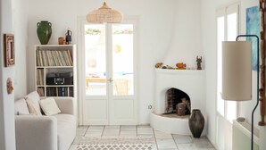 Un salon comprenant un canapé, une bibliothèque, une cheminée et une porte donnant sur l’extérieur.