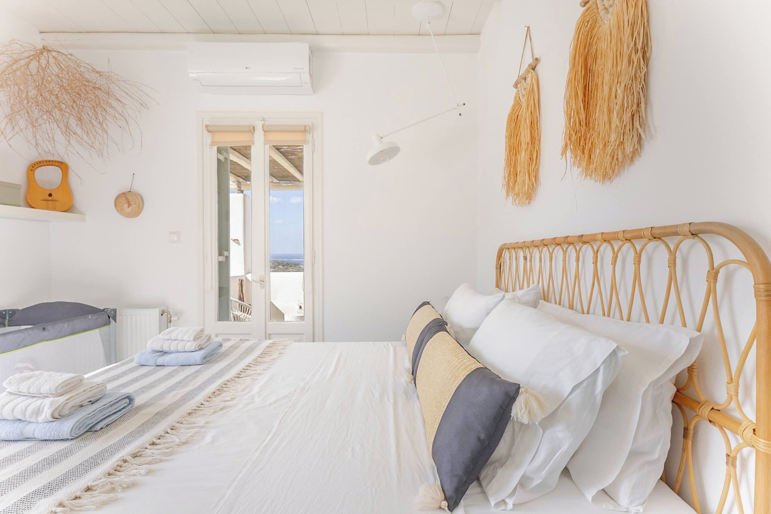 A bedroom with a bed, towels, a view through a door, and a ceiling fan.
