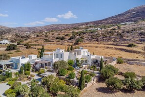A white building with a flat roof and a small garden area with potted plants. - Sea-View Cycladic Villa near Alyki – Family Home with Olive Garden & Starlink (Paros)