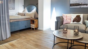 Een moderne woonkamer met een bank, een bijzettafeltje met kaarsen en een bed met hoofdeinde.
